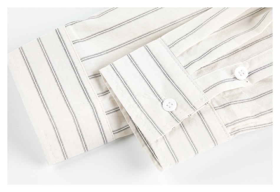 Close-up of striped off-white shirt cuffs with white buttons and matching narrow stripes.