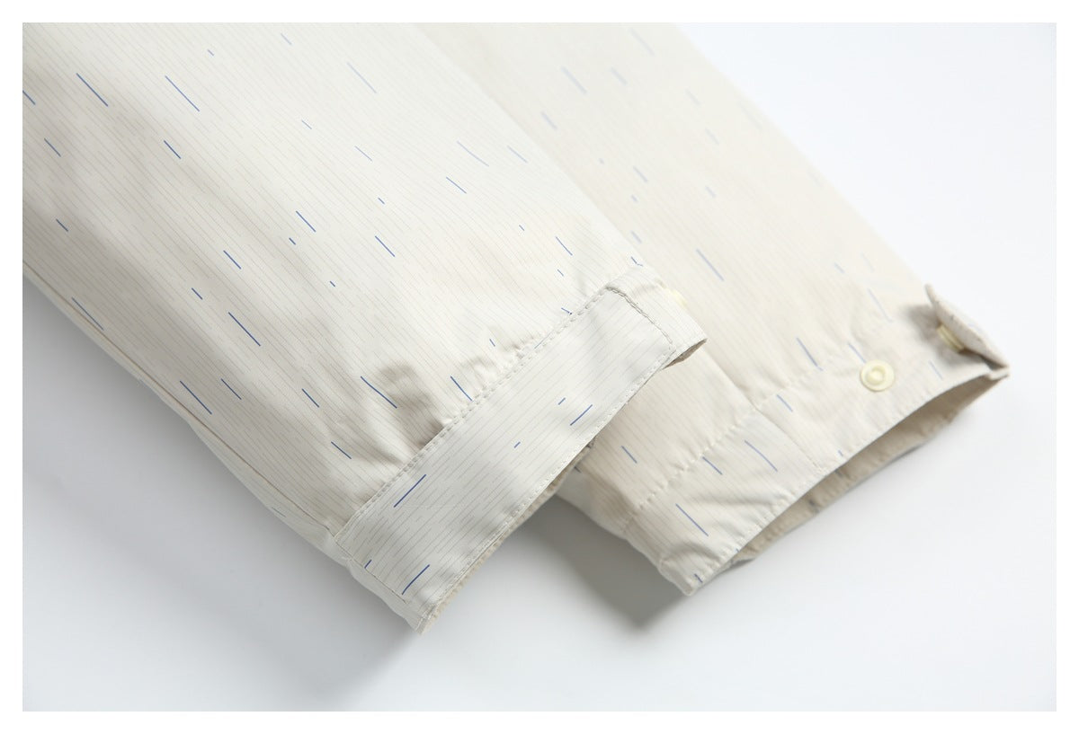Close-up of a cream jacket sleeve cuff with a button and fine-line pattern accented by blue dashes.