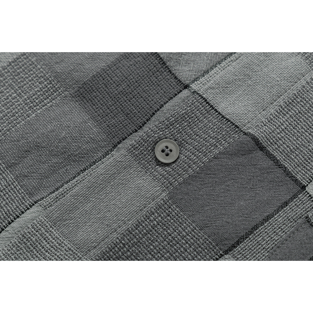 Close-up of a dark gray button on the shirt's textured gray check pattern.