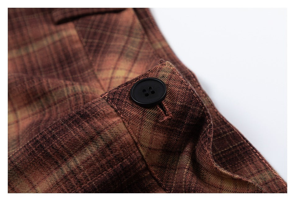 Close-up of a black button on brown and tan plaid trousers.