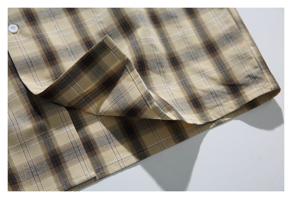 Close-up of the beige plaid shirt hem and folded fabric, showing the check pattern and stitching.