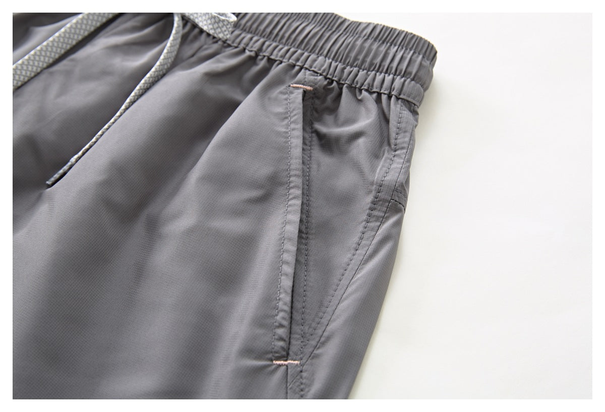 Close-up of a gray shorts side pocket with stitched edges and small pale pink bar tacks.