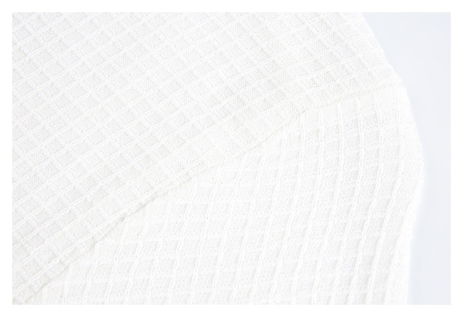 Close-up of white knit fabric showing a raised grid texture and a diagonal seam.