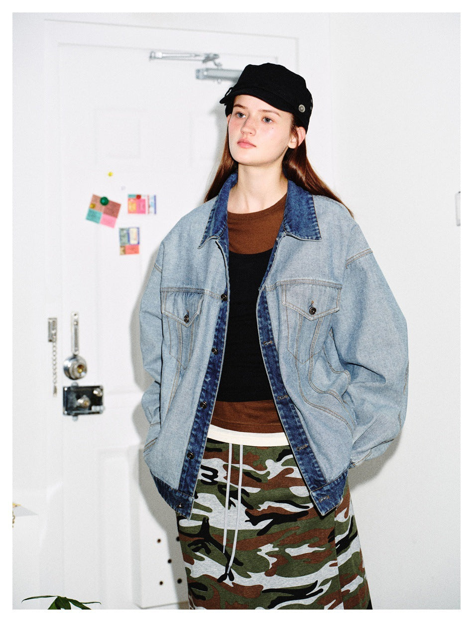 Model wearing an oversized light blue denim jacket over a brown and black top with a camo skirt and black cap