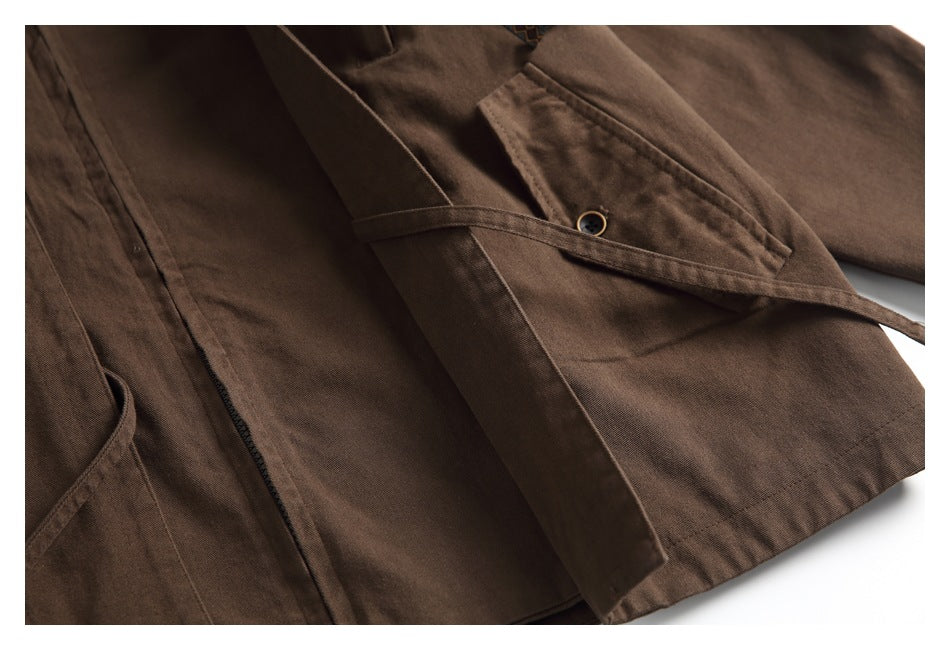 Partial flat lay of a brown jacket showing the front, flap pocket, and long front panels.