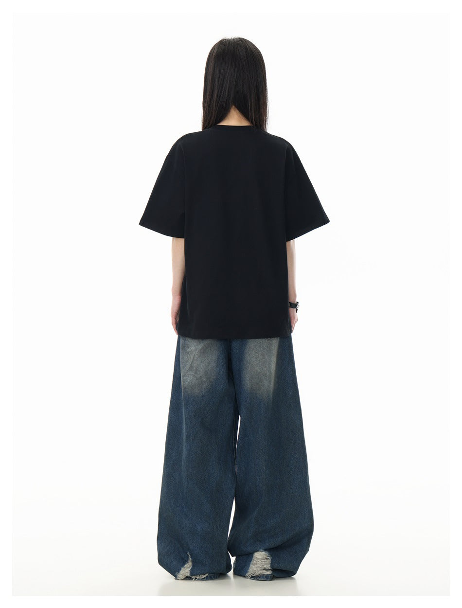 Rear view of a model wearing a plain oversized black T-shirt and wide-leg blue jeans.
