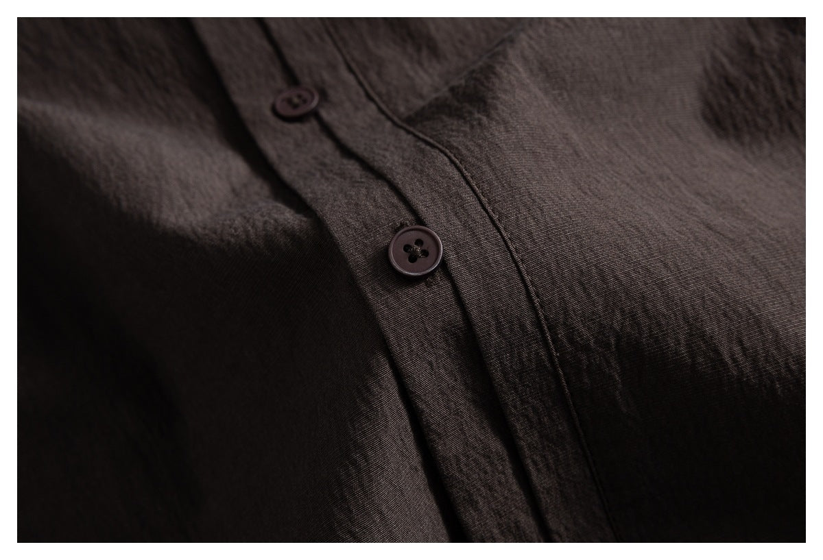 Close-up of two dark buttons and the placket on a dark brown shirt.