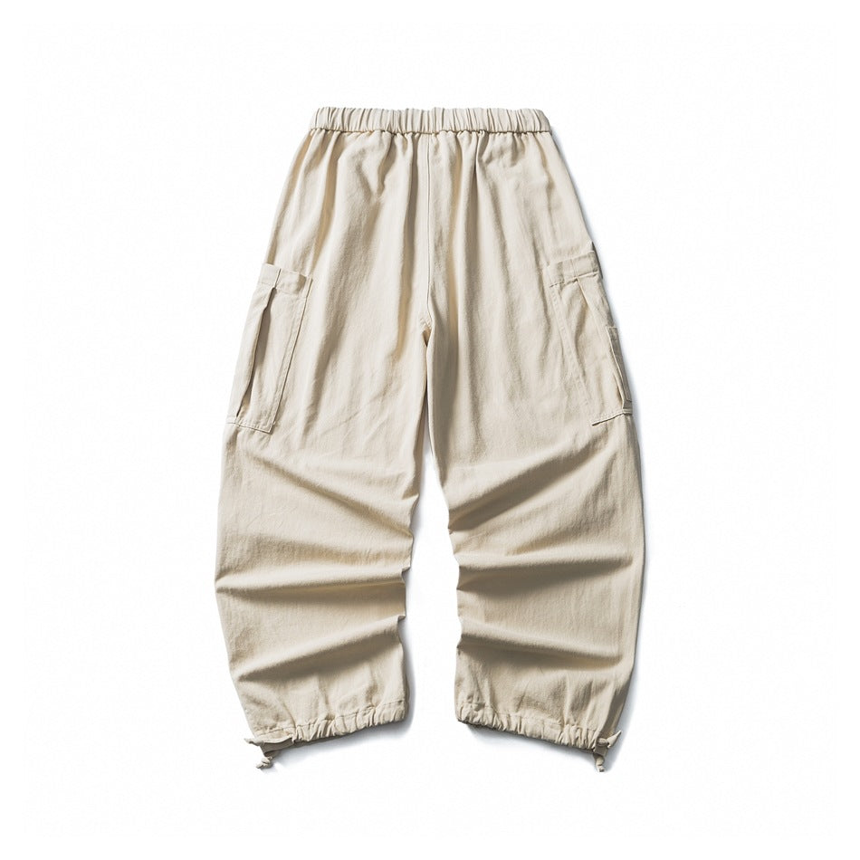 Cream loose-fit cargo pants with an elastic waistband, side pockets, and gathered adjustable ankle hems, shown flat.