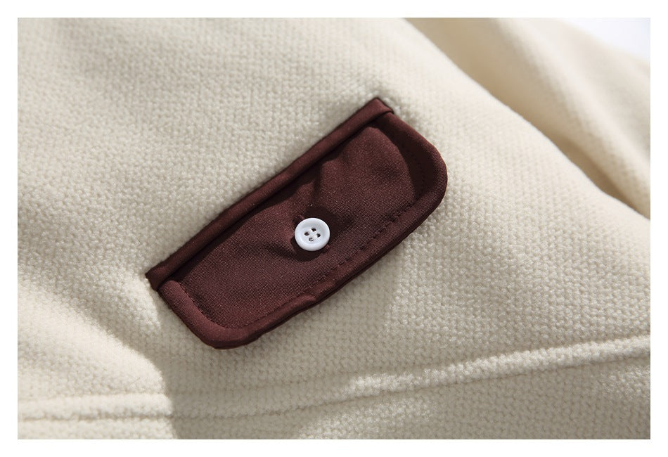 Close-up of a dark brown buttoned flap on a cream textured garment.