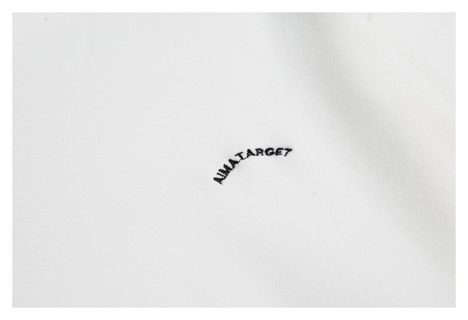 Close-up of small black embroidered lettering on white fabric.