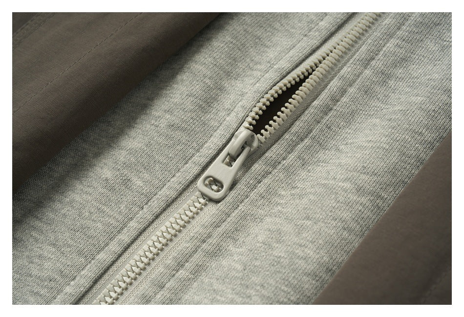 Close-up of a pale chunky zipper on heather gray knit fabric.