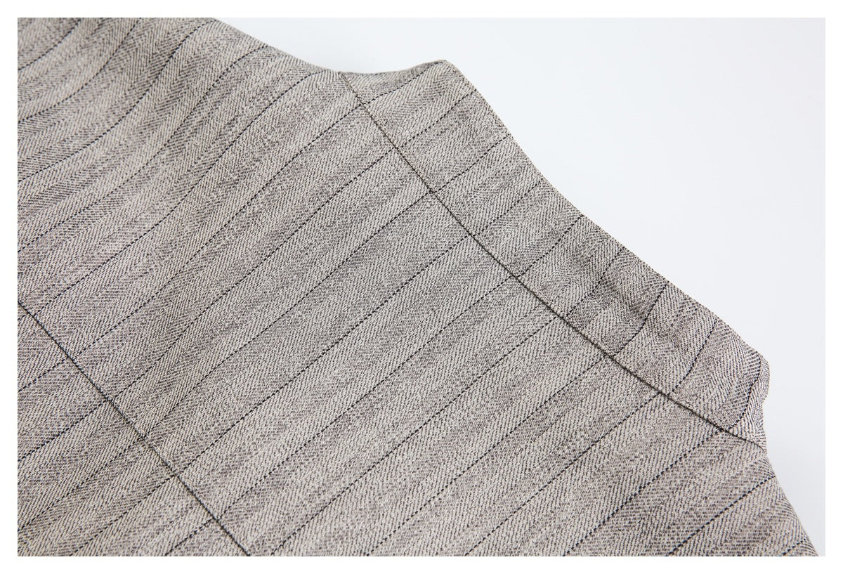 Close-up of beige-gray fabric with fine dark stripes and visible intersecting seams.