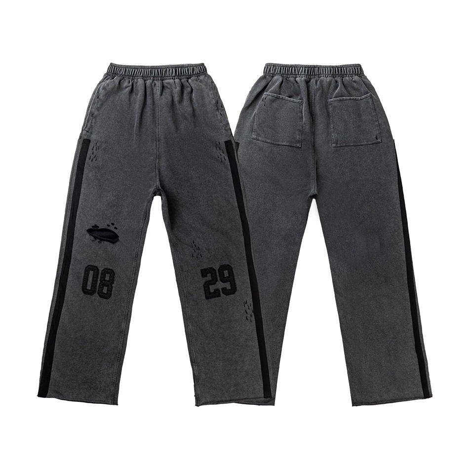 Charcoal-gray pants shown flat with front and back views, black side stripes, distressed details, and number patches.