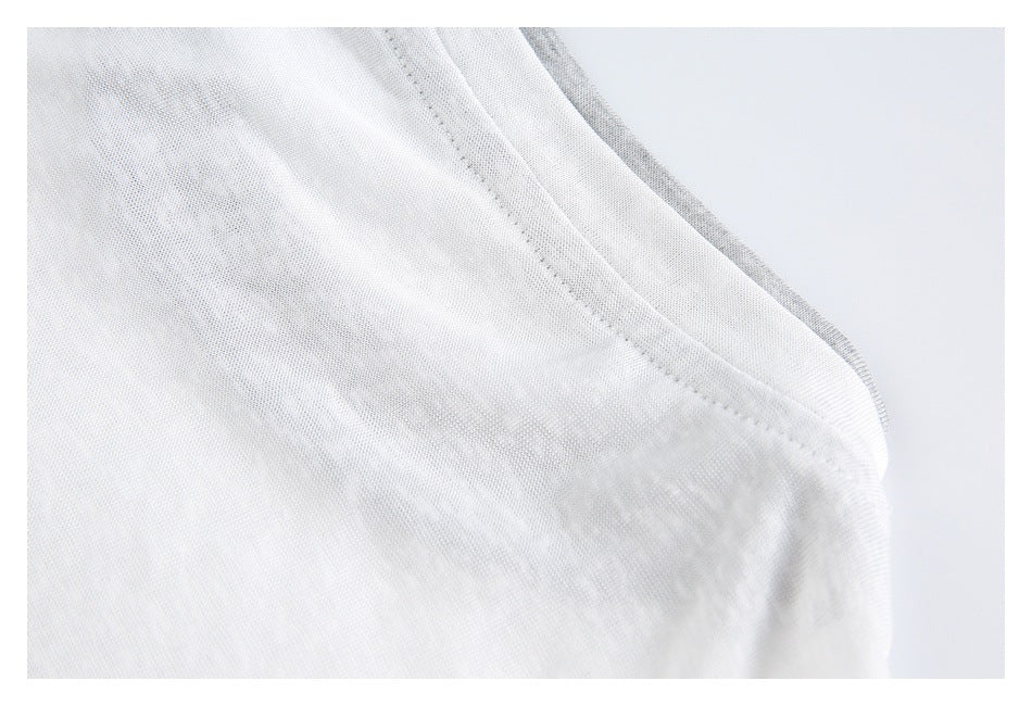 Close-up of a white garment seam curving around an edge, with gray fabric visible underneath.