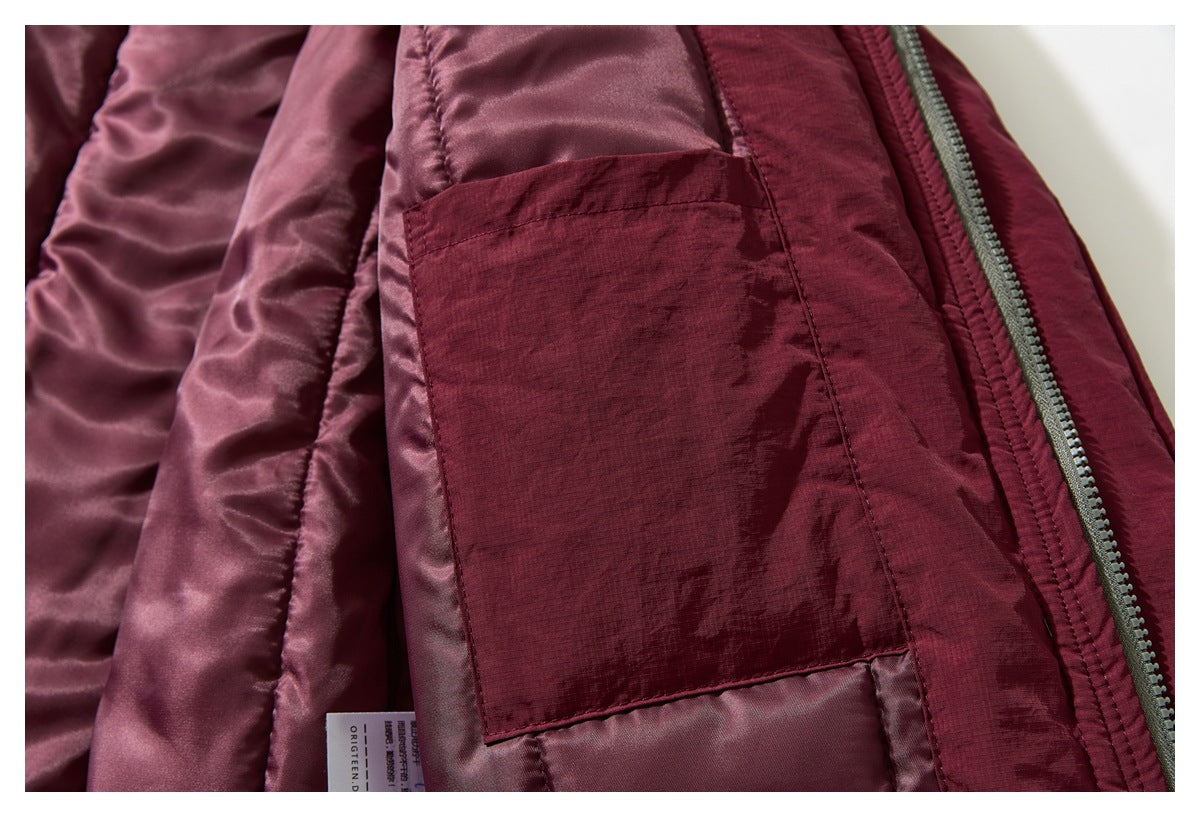 Close-up inside a burgundy jacket, showing shiny lining, an interior pocket, and a zipper.