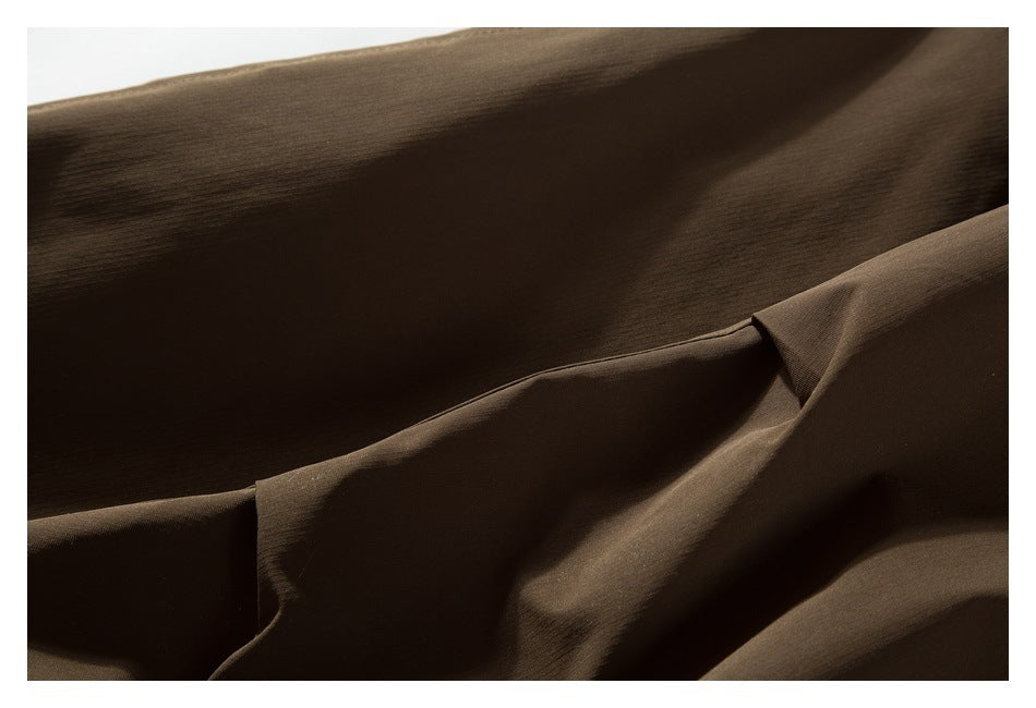 Close-up of dark brown garment fabric showing a stitched seam and folded panel.