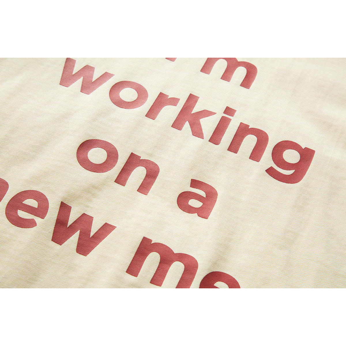 Close-up of red English lettering printed on ivory T-shirt fabric.