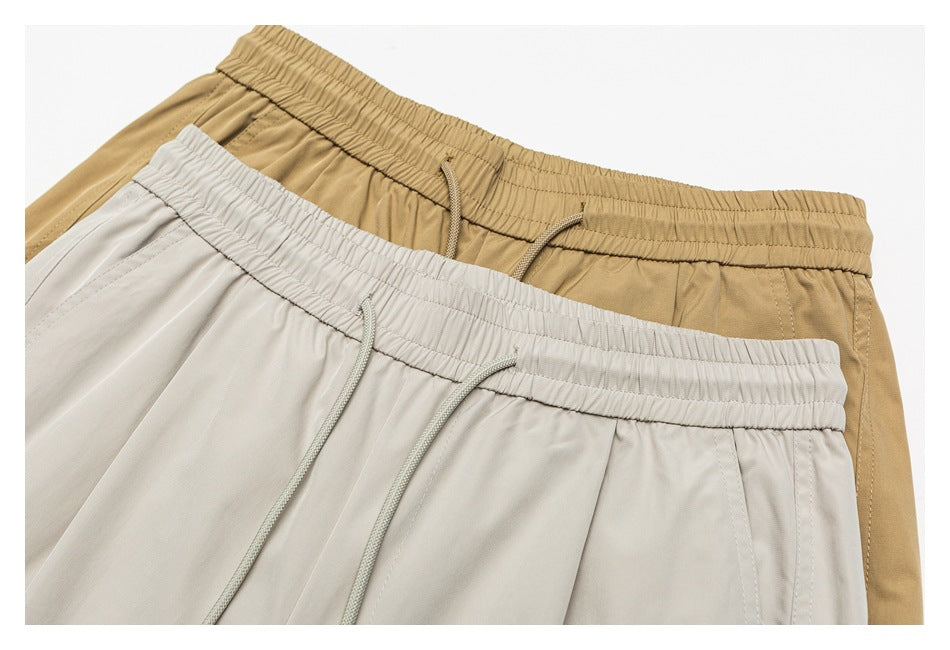 Close-up of tan and light gray pants showing elastic drawstring waistbands and front seams.