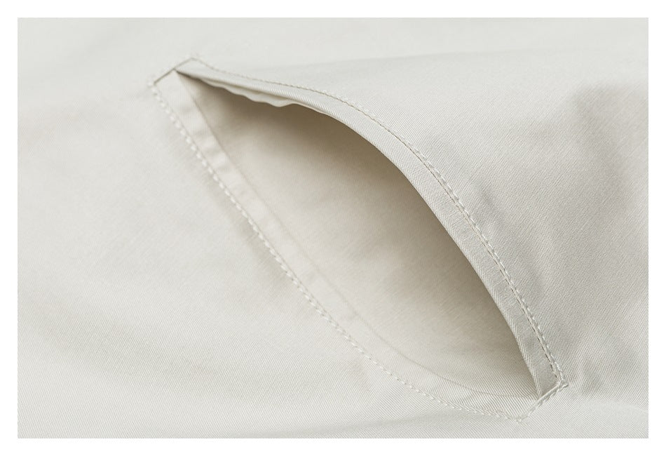 Close-up of a slanted welt pocket on pale beige jacket fabric.