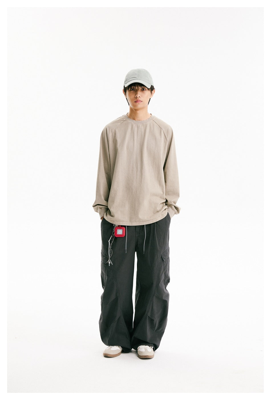 Front view of a model wearing a loose beige long-sleeve raglan shirt and dark cargo pants.