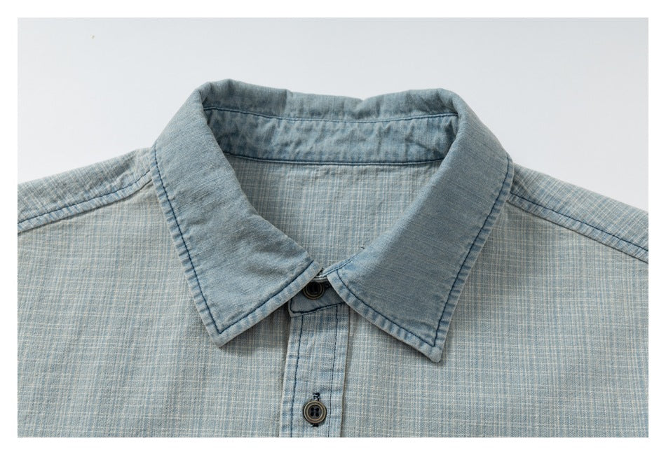 Close-up of the light blue crosshatch shirt's pointed collar and upper button placket.