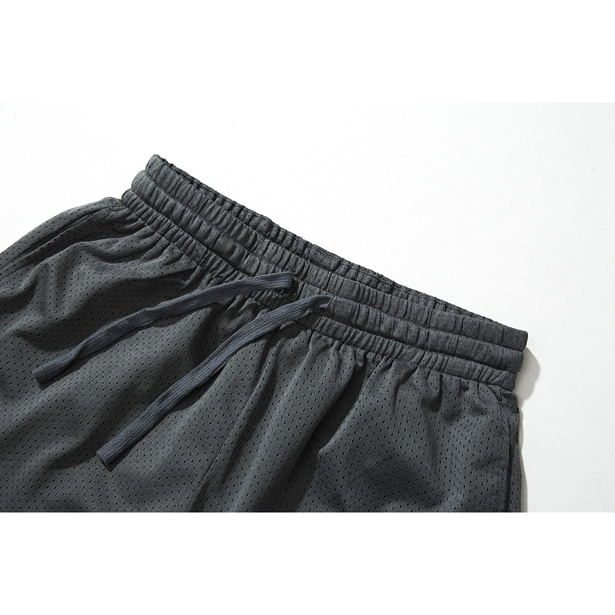 Close-up of charcoal mesh shorts showing the elastic waistband and matching drawstring.