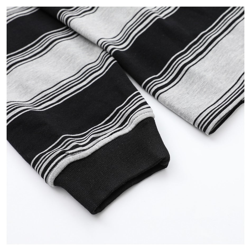 Close-up of striped sleeves ending in solid black cuffs on a black and heather-gray top.