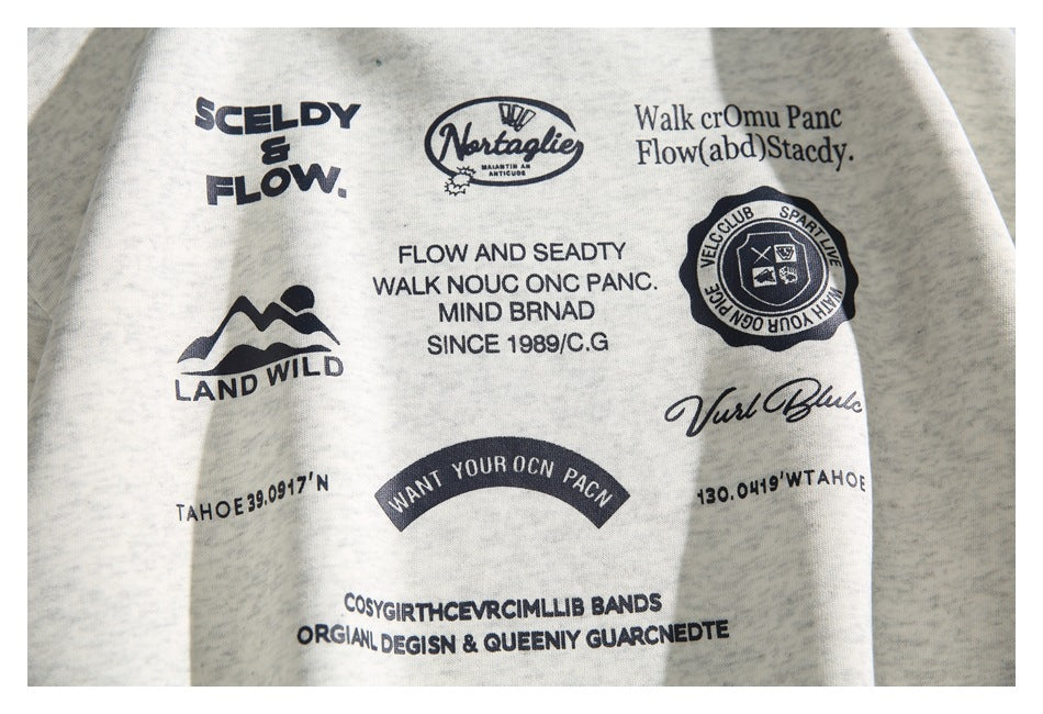 Close-up of assorted dark text, emblems, and mountain graphics printed on heathered light-gray sweatshirt fabric.