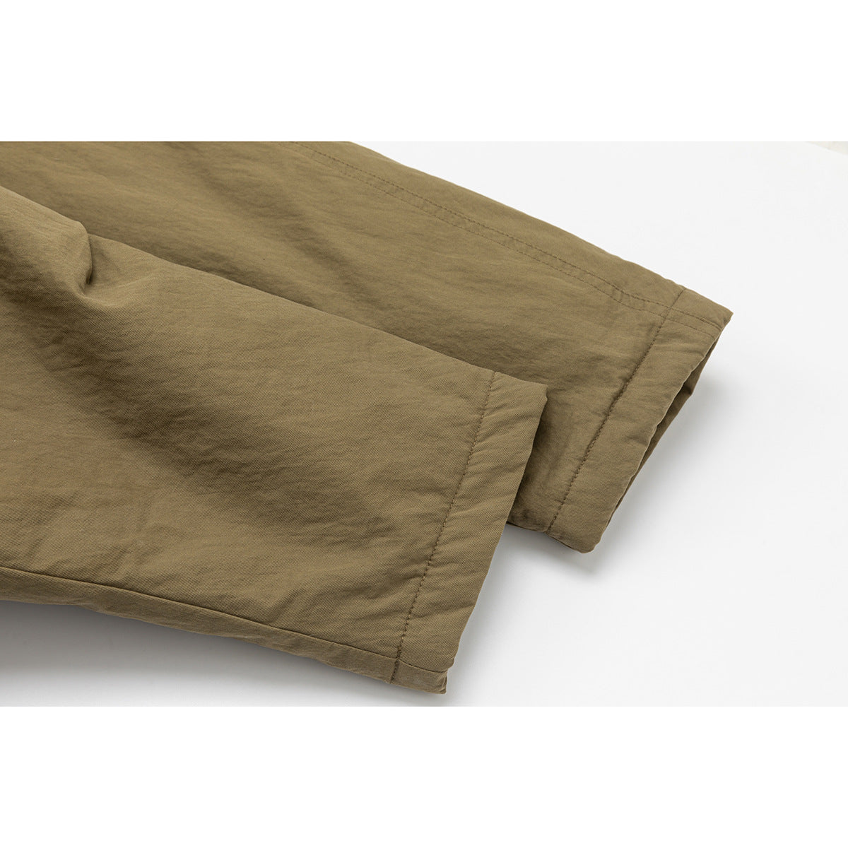 Close-up of the olive-brown coat's sleeve cuffs, showing folded hems and visible stitching.