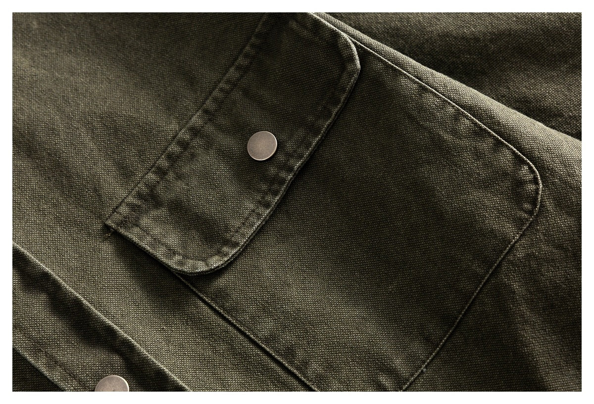 Close-up of an olive-gray shirt's large flap pocket and metal snap button.