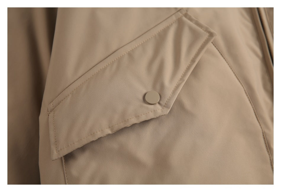 Close-up of a tan jacket's angled pocket flap with a round snap button and visible stitching.