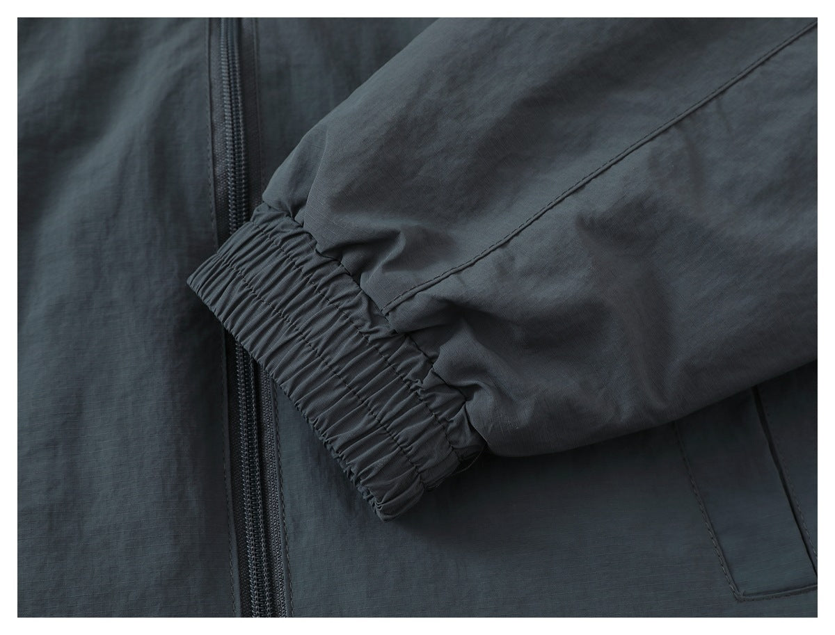 Close-up of a charcoal gray jacket sleeve with an elasticated cuff beside the front zipper.