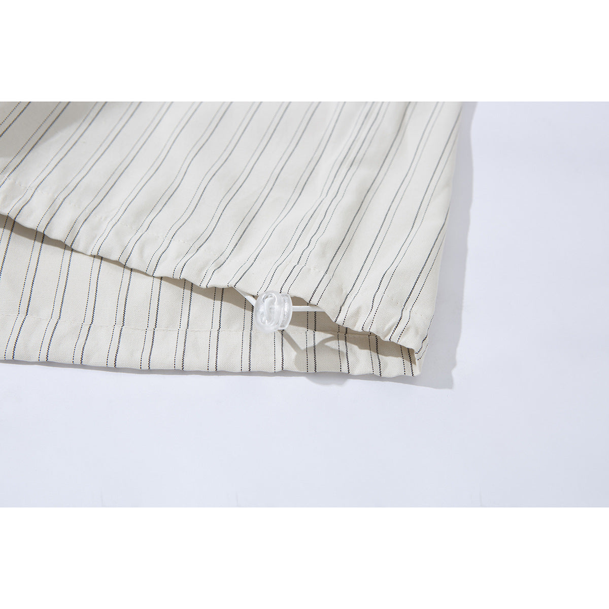 Close-up of the striped off-white shirt hem with a small white cord adjuster.