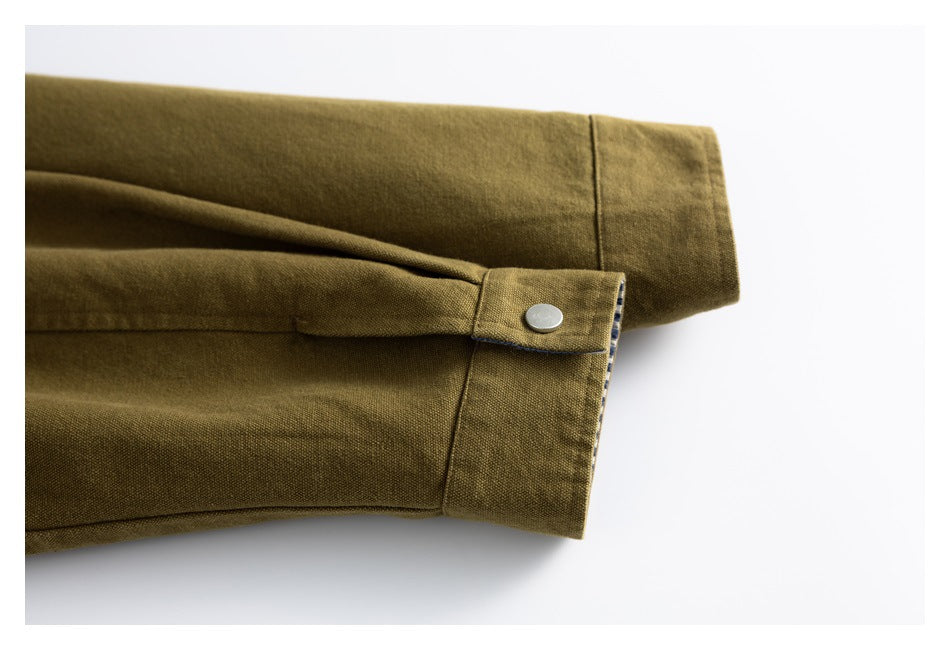 Close-up of an olive-brown jacket sleeve cuff with a silver snap tab and striped trim.