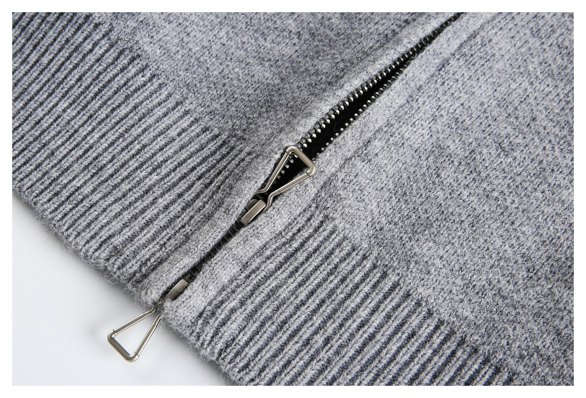 Close-up of a gray knit garment with a zipper and metal pull beside a wide ribbed edge.