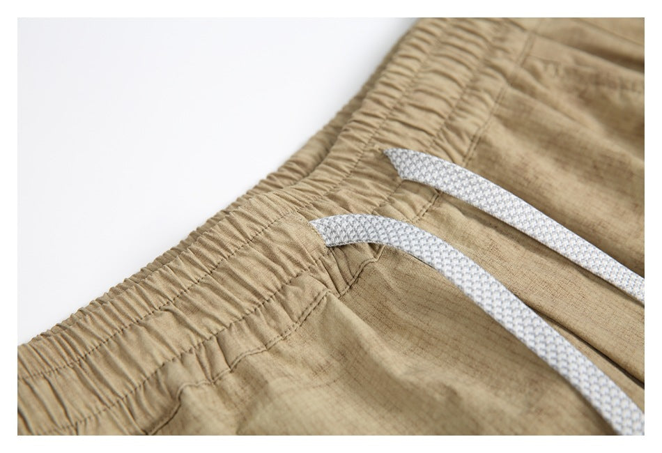 Close-up of the elastic waistband and white drawstrings on the tan pants.