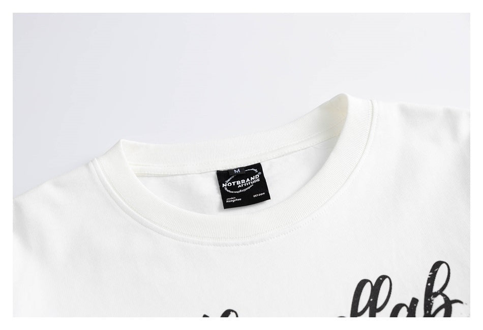 Close-up of a white long-sleeve shirt's ribbed crew neck, black neck label and partial black chest lettering.