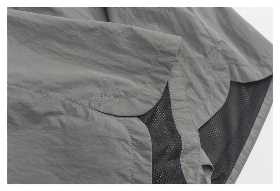 Close-up of gray shorts showing the hem, seams, and black mesh lining.
