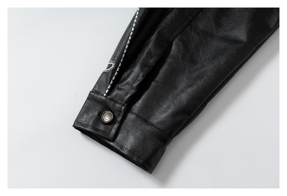 Close-up of a black jacket sleeve cuff with a button and white contrast stitching.