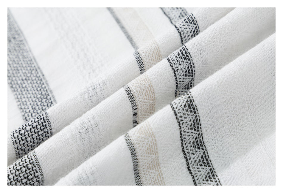 Close-up of white shirt fabric with textured black and beige woven stripes and a visible fold.