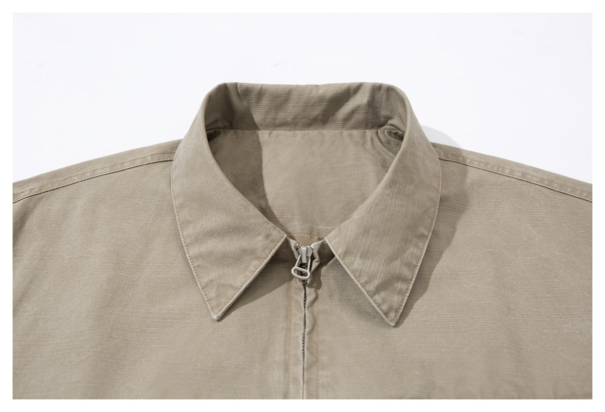 Close-up of the taupe jacket's pointed collar and front zipper with a loop-shaped pull.