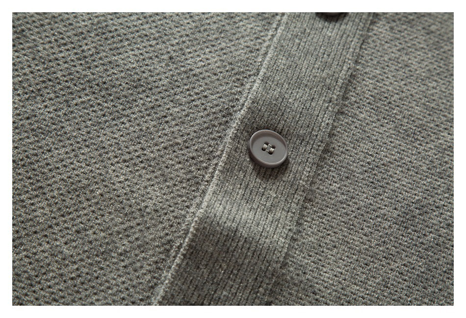 Close-up of a gray knit cardigan's button and textured placket.
