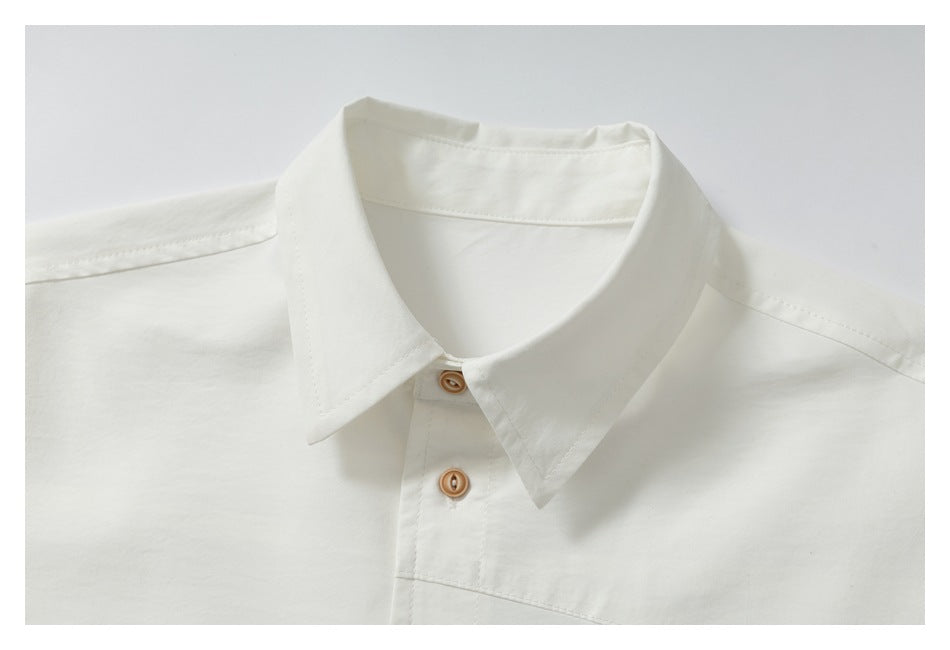 Close-up of an off-white shirt collar and upper placket with tan buttons.