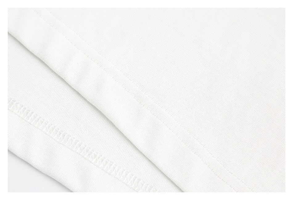 Close-up of white garment fabric showing a folded edge and visible stitching.