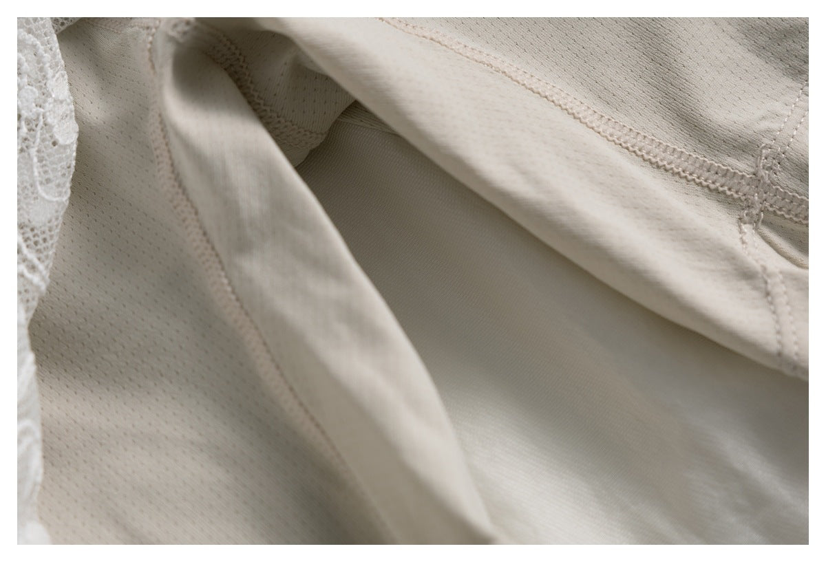 Close-up of the cream garment's interior, showing seams, a mesh-textured panel, and a glimpse of white lace.