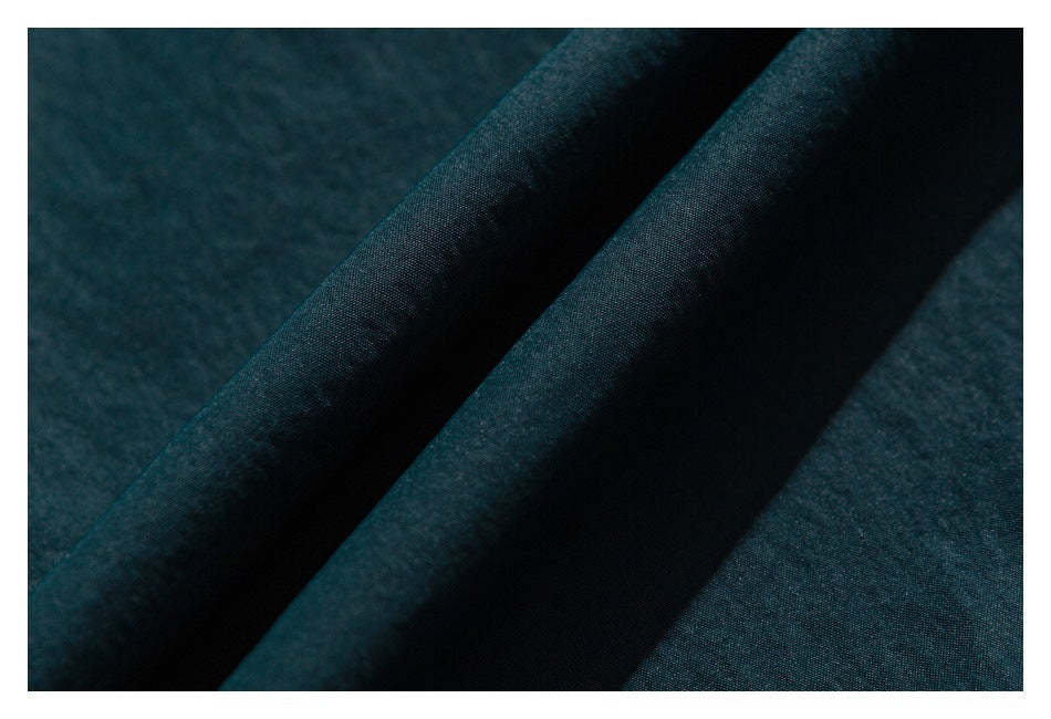 Close-up of dark teal fabric folded to show its surface and texture.