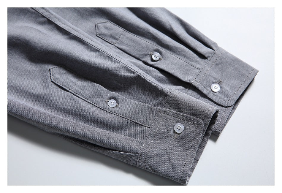 Close-up of two gray shirt cuffs with button closures and stitched edges.