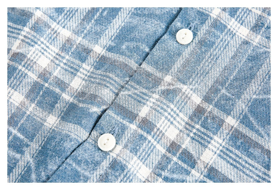 Close-up of two white buttons and the blue-and-white plaid fabric on the shirt.