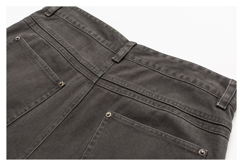 Close-up of dark charcoal pants showing the waistband, belt loops, seams and metal-riveted pockets.