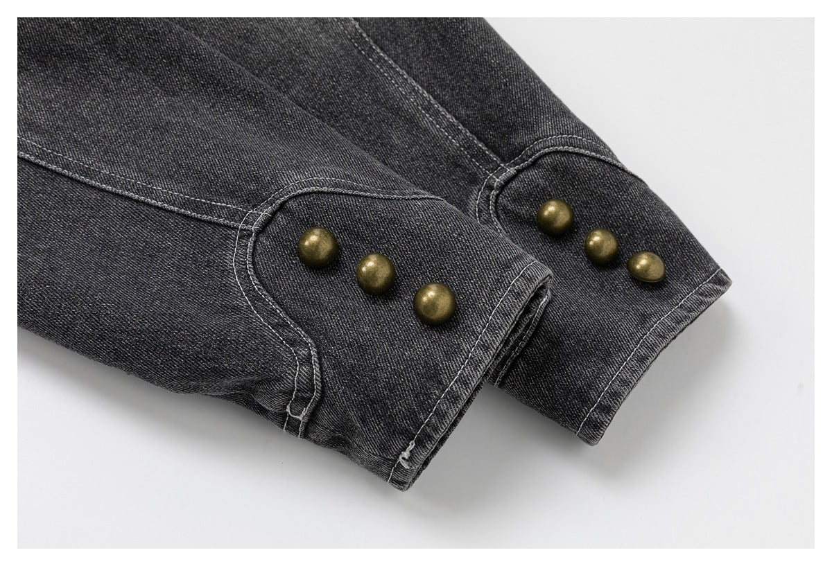 Close-up of charcoal denim cuffs with contrast stitching and rows of brass-tone buttons.